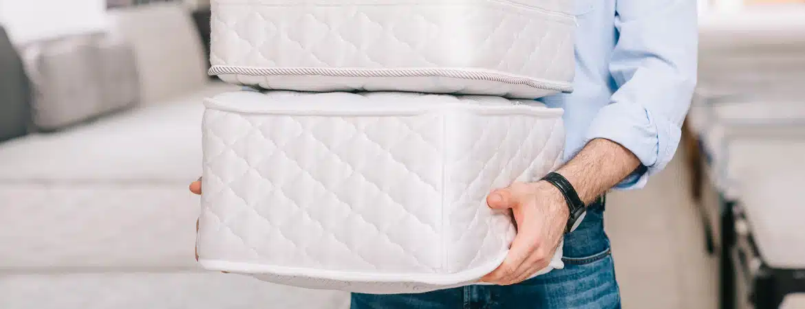 Man holding pile of folding mattress